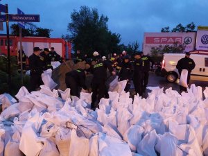 worki z nasypanym piaskiem, grupa strażaków i policjantów, którzy nasypują piasek do worków