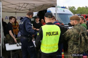 Na zdjęciu grupa osób, w tym na pierwszym planie policjant wysyłający w teren grupy poszukiwawczo-ratownicze