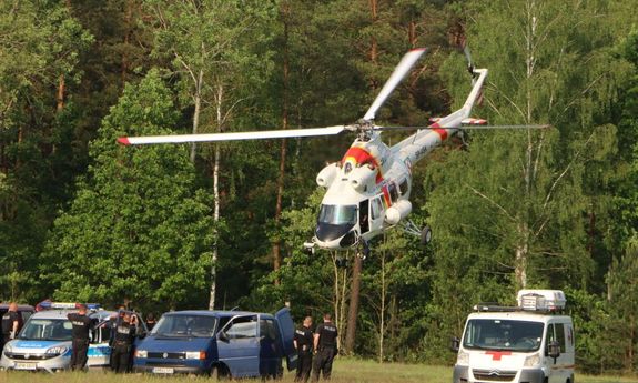 Śmigłowiec straży granicznej ląduje podczas ćwiczeń,  na lądowisku stoją pojazdy służbowe.