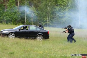 Na zdjęciu widoczny w oddali pojazd ze sprawcą zatrzymywany przez umundurowanych i uzbrojonych policjantów z Oddziałów Prewencji Policji KWP Białystok