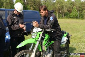 Na zdjęciu policjanci z urządzeniami gps przed wyjściem w sektor poszukiwań. Jeden z nich siedzi na oznakowanym napisem Policja motocyklu