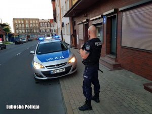 policjant stoi przed radiowozem