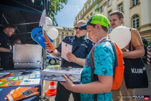 Dziecko wraz z policjantką przy stoisku Biura Prewencji KGP