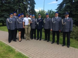 grupa policjantów w mundurach galowych jeden z nich trzyma puchar