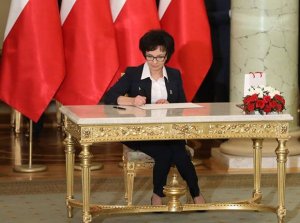 minister Ewa Witek podpisuje rotę przysięgi siedząc przy złotym stoliku