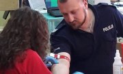 Policjant w mundurze oddaje krew w obecności pielęgniarki w czerwonym kitlu