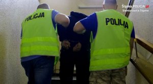 dwaj policjanci prowadzą zatrzymanego mężczyznę