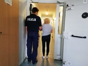 Policjant wykonujący czynności z zatrzymaną kobietą