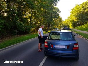 st. sierż. Paweł Olejniczak stojący przy samochodzie, którym kierował nietrzeźwy mężczyzna