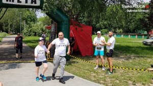 jeden z zawodników biegnie z chłopcem trzymając go za rękę