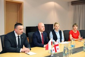 Komendant Główny Policji gen. insp.  Jarosław Szymczyk, Komendant Centralnego Biura Śledczego Policji insp. Paweł Półtorzycki oraz Dyrektor Biura Międzynarodowej Współpracy Policji KGP mł.insp. Paulina Filipowiak i tłumaczka siedzą przy stole w urzędzie. Na stole flaga gruzińska i polska.