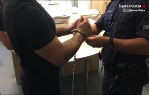 Policjant zakłada na podejrzanemu kajdanki