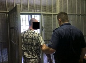 Policjant z zatrzymanym mężczyzną  w pomieszczeniu dla osób zatrzymanych