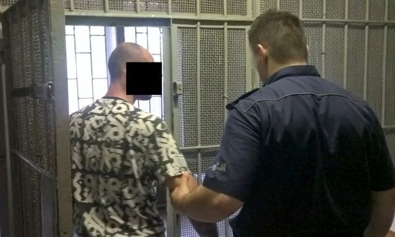 Policjant z zatrzymanym mężczyzną  w pomieszczeniu dla osób zatrzymanych