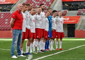 Zdjęcie przedstawia zawodników drużyny Policji obserwujących zmagania na boisku oraz czekających w gotowości do zmiany kolegi z drużyny.