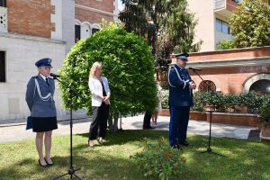 Komendant Wojewódzki Policji w Katowicach nadinsp. Krzysztof Justyński przemawia stojąc przy mikrofonie obok stoi polska policjantka i inna kobieta