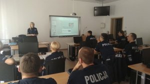 uczestnicy szkolenia siedzą w ławkach podczas wykładu, policjantka stoi i mówi do nich