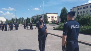 uczestnicy szkolenia na placu stoją jeden z nich stoi naprzeciwko innego policjanta z szablą uniesiona do góry