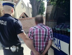 policjant prowadzi zatrzymanego