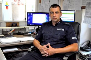 Policjant, który zatrzymał nietrzeźwego kierującego. Siedzi na fotelu przy biurku dyżurnego