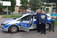policjantka stoi przy radiowozie z młodzieżą