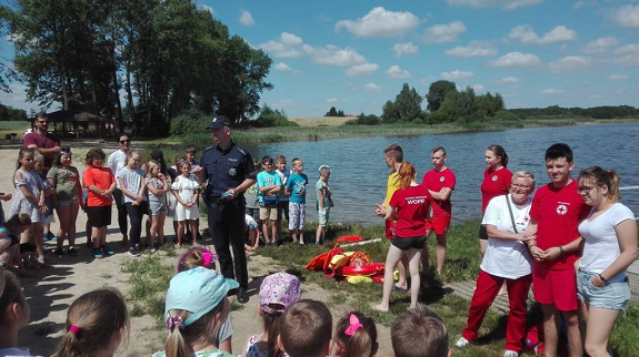 Policjant w trakcie spotkania z dziećmi nad brzegiem jeziora.