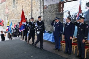 czescy policjanci wchodzą na scenę ze sztandarem, obok nich salutują dwaj policjanci z Polski i z Czech. Między nimi stoi mężczyzna w garniturze