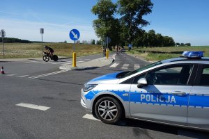 policjanci w radiowozie zabezpieczają przejazd kolarzy