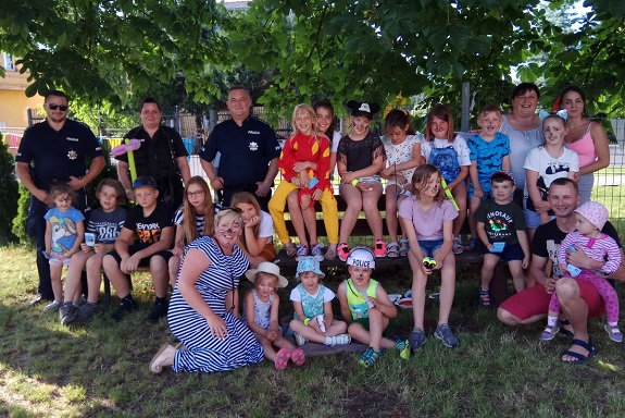 Na zdjęciu widoczna jest grupa dzieci z opiekunami i dwoma policjantami.