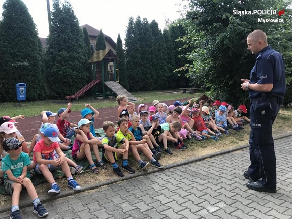 Na zdjęciu widoczna grupa dzieci w trakcie spotkania z policjantem.