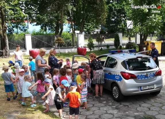 policjant z dziećmi przy radiowozie prowadzi działania profilaktyczne