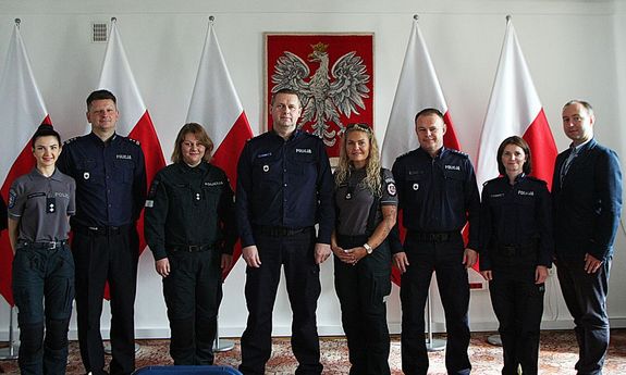 litewscy oraz polscy policjanci w Komendzie Głównej Policji pozują do zdjęcia  w tle godło Polski oraz flagi