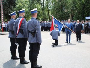 komendant powiatowy policji w Hajnówce klęcząc całuje sztandar