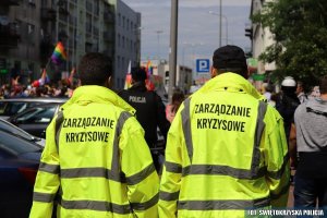 dwóch mężczyzn odwróconych tyłem w żółtych kurtkach z napisem Zarządzanie Kryzysowe