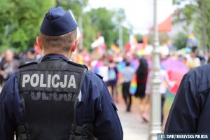 odwrócony, umundurowany policjant w kamizelce taktycznej z napisem na plecach POLICJA