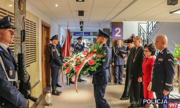 Szef Policji , księża i Minister Spraw Wewnętrznych i Administracji składają wieniec pod Tablicą Pamięci w KGP