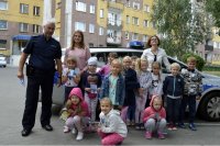 policjant stoi z grupą dzieci przed radiowozem