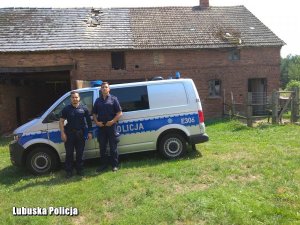 Zdjęcie przestawia policjantów, którzy ugasili pożar. W tle widoczny jest radiowóz i budynek gospodarczy.