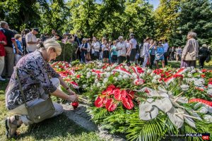 grupa ludzi i złożone kwiaty