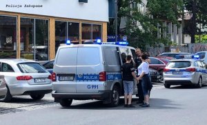 policjant przy radiowozie policyjnym rozmawia z ludźmi