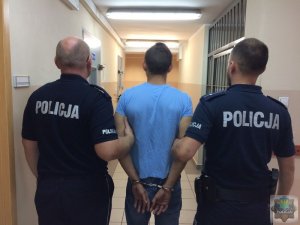 Dwaj policjanci prowadzą zatrzymanego mężczyznę.