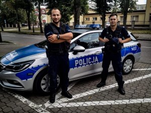 dwaj policjanci stoją przy radiowozie