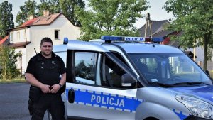 policjant stoi przy radiowozie