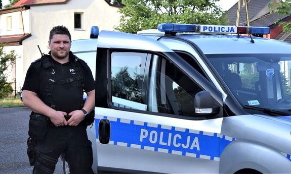 policjant stoi przy radiowozie