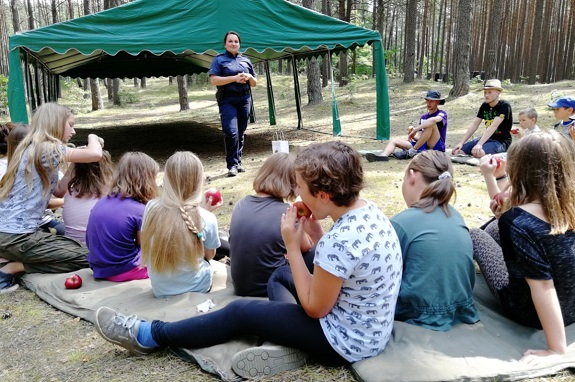 Na zdjęciu widoczna jest policjantka rozmawiająca z dziećmi.