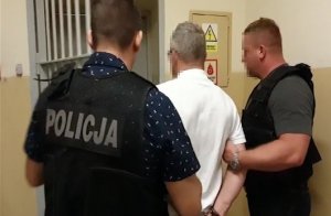dwaj policjanci z zatrzymanym mężczyzną