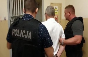 dwaj policjanci z zatrzymanym mężczyzną