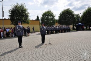 policjant przemawia przez mikrofon w tle grupa policjantów i zaproszeni goście uroczystości