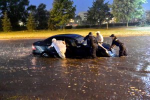 Policjanci pomagający wypchnąć podtopiony pojazd