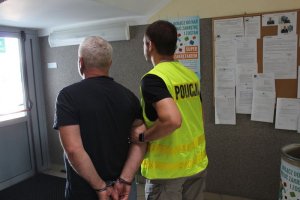 policjant prowadzi zatrzymanego mężczyznę